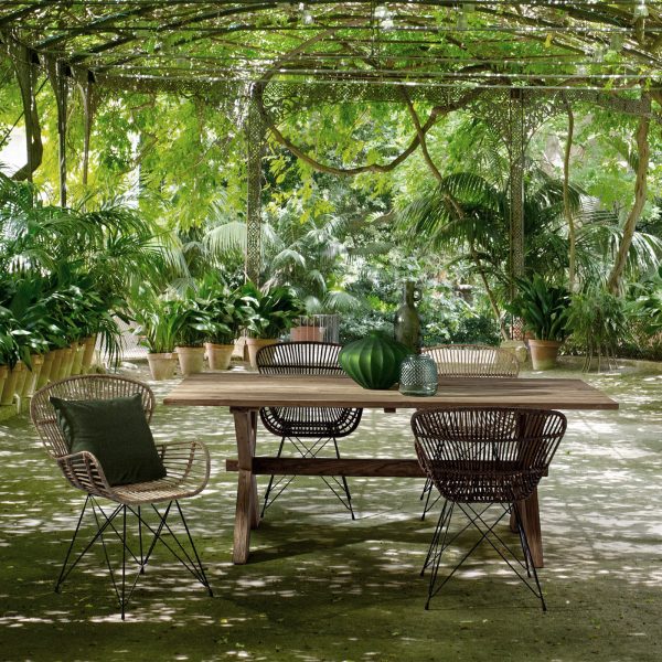Ambiente exterior de DL interior Design con unas sillas de ratán y una mesa de madera en un jardín